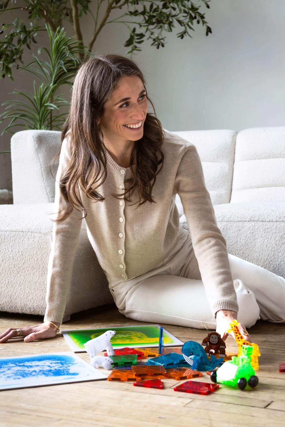 Kathryn Ressa, smiling, sitting on the floor with childrens toys spread in the front.