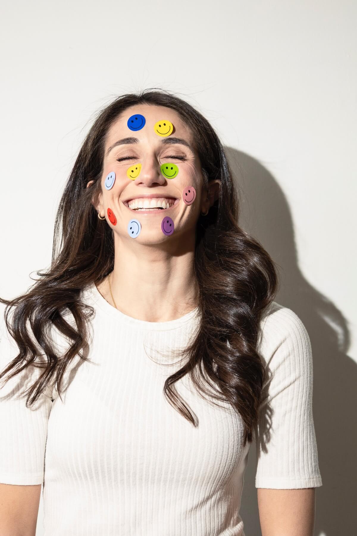 Kathryn Ressa, smiling with smiley stickers on her face.